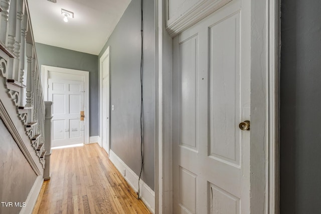 corridor with stairs, light wood-type flooring, and baseboards