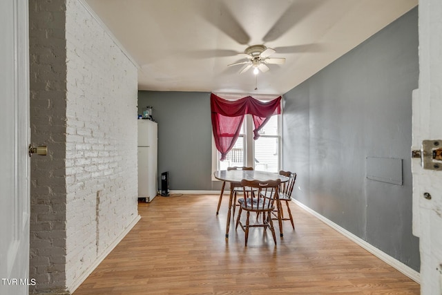 dining space with baseboards, a ceiling fan, and wood finished floors
