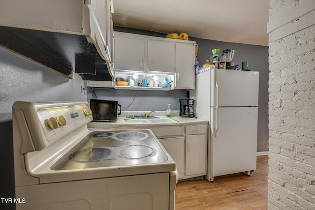 kitchen with white appliances, light wood-style flooring, light countertops, white cabinetry, and a sink