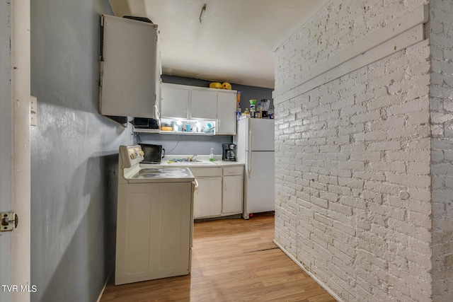 kitchen with washer / clothes dryer, white cabinetry, freestanding refrigerator, light wood-style floors, and electric stove