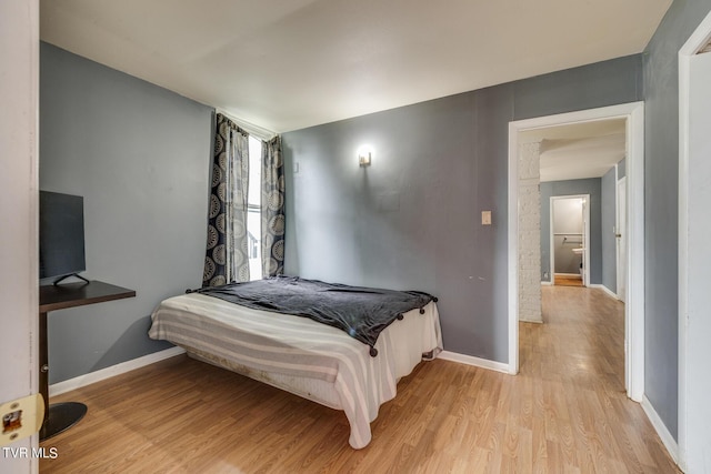 bedroom featuring light wood finished floors and baseboards