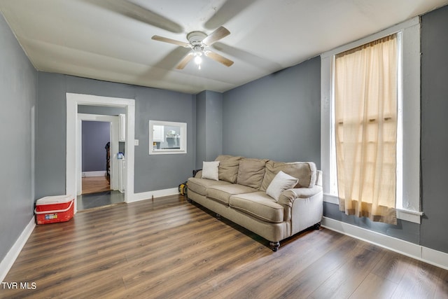 living area featuring ceiling fan, baseboards, and wood finished floors
