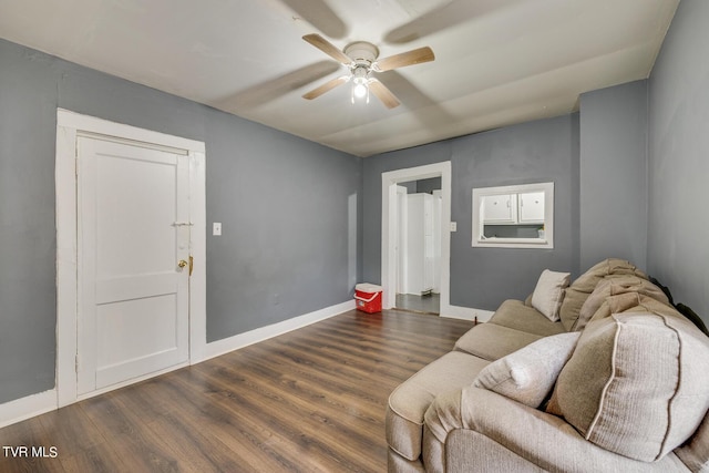 living area featuring dark wood-style floors, baseboards, and ceiling fan