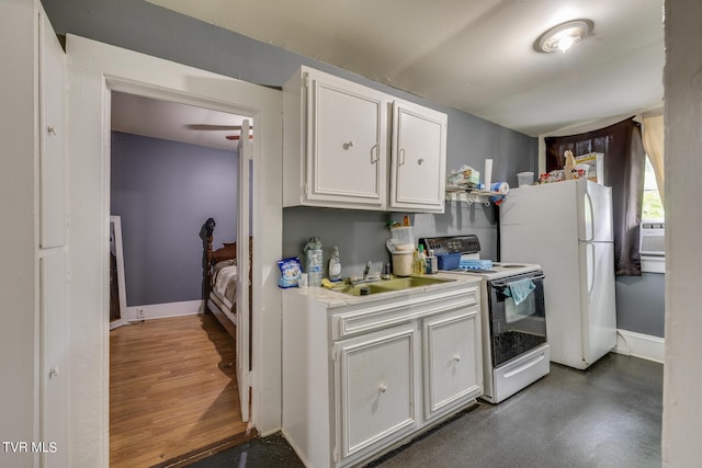 kitchen with range with electric stovetop, a sink, light countertops, freestanding refrigerator, and white cabinetry