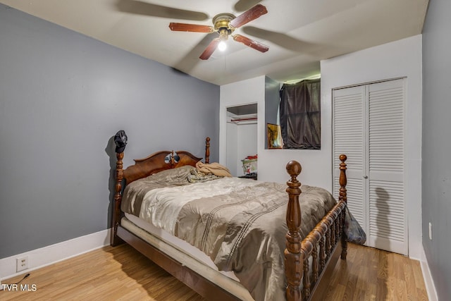 bedroom with baseboards, two closets, a ceiling fan, and wood finished floors