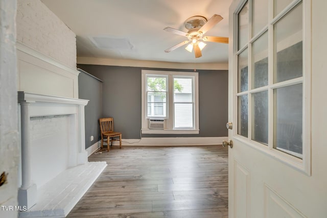 unfurnished living room with baseboards, a ceiling fan, cooling unit, and wood finished floors