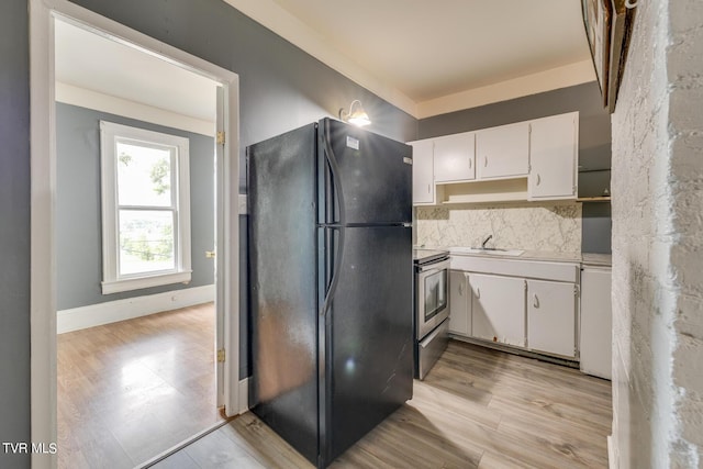 kitchen featuring light wood-style flooring, stainless steel electric range, freestanding refrigerator, and white cabinetry