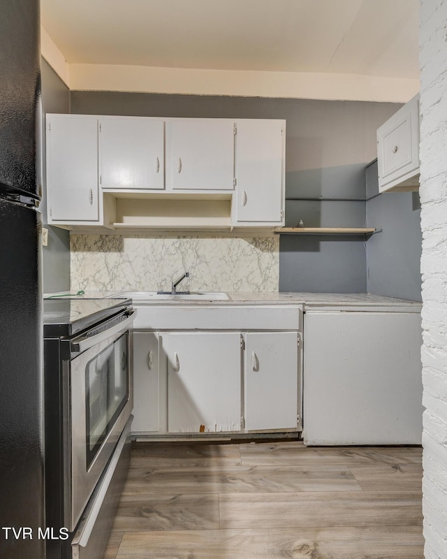 kitchen featuring a sink, white cabinets, open shelves, and stainless steel range with electric cooktop