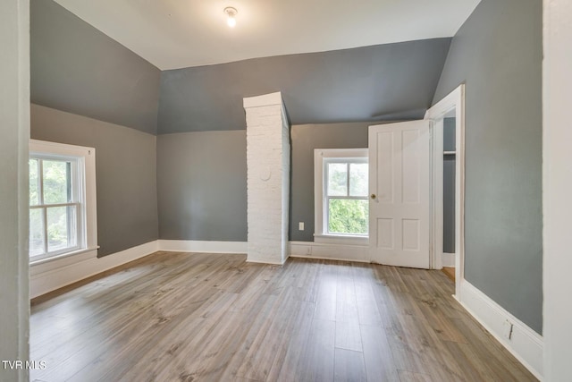 unfurnished bedroom with wood finished floors, baseboards, and lofted ceiling