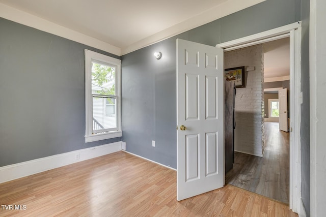 unfurnished room featuring baseboards, light wood finished floors, and a healthy amount of sunlight