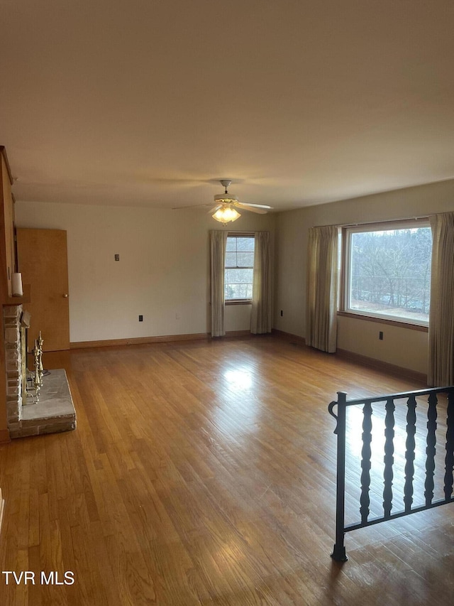 unfurnished living room with ceiling fan, plenty of natural light, a fireplace, and light hardwood / wood-style flooring