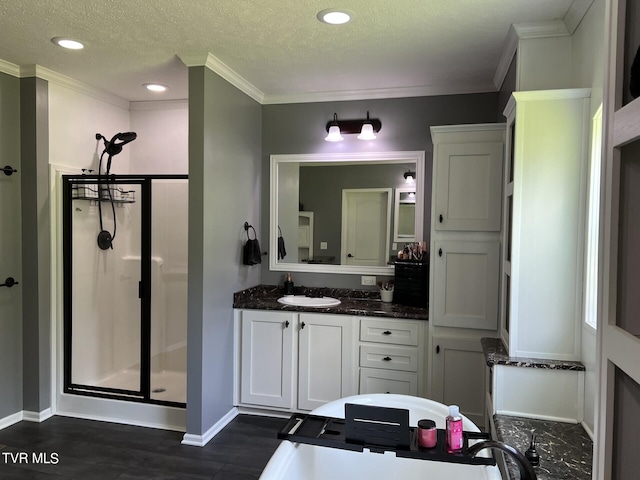 bathroom with crown molding, hardwood / wood-style floors, walk in shower, vanity, and a textured ceiling