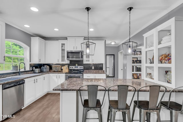 kitchen featuring stainless steel appliances, hanging light fixtures, a kitchen bar, ornamental molding, and sink