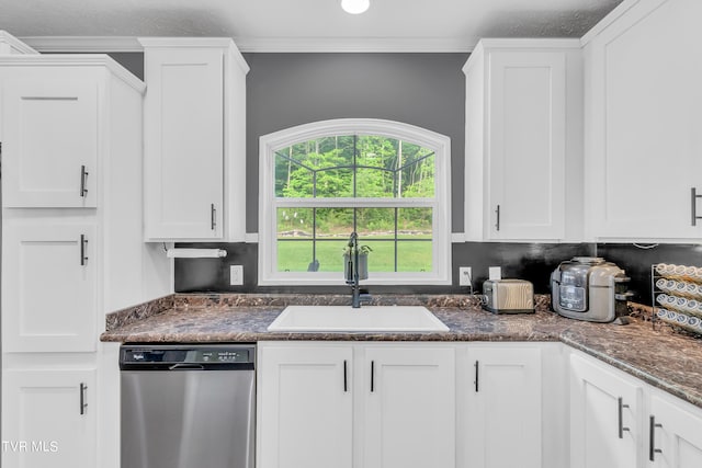 kitchen with dark stone counters, crown molding, stainless steel dishwasher, sink, and white cabinets