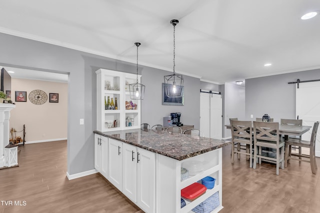 kitchen with a barn door, hardwood / wood-style floors, and white cabinets