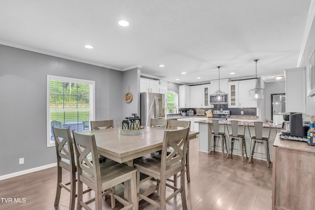 dining room with sink, ornamental molding, and dark hardwood / wood-style floors