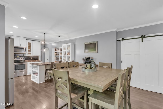 dining room featuring a barn door, crown molding, and hardwood / wood-style floors