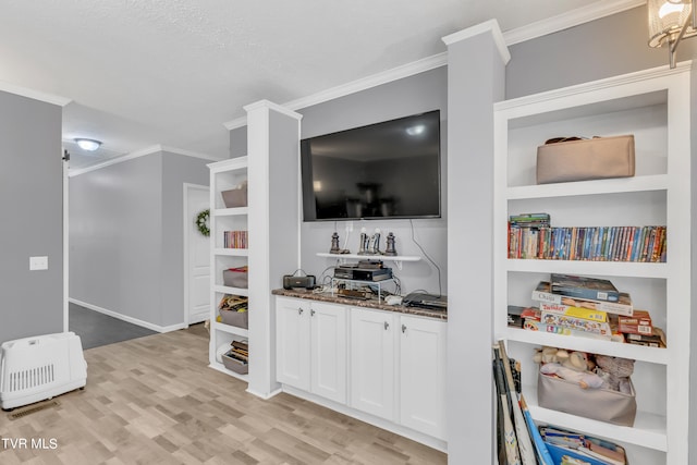 kitchen featuring light hardwood / wood-style floors, white cabinetry, dark stone countertops, crown molding, and built in shelves