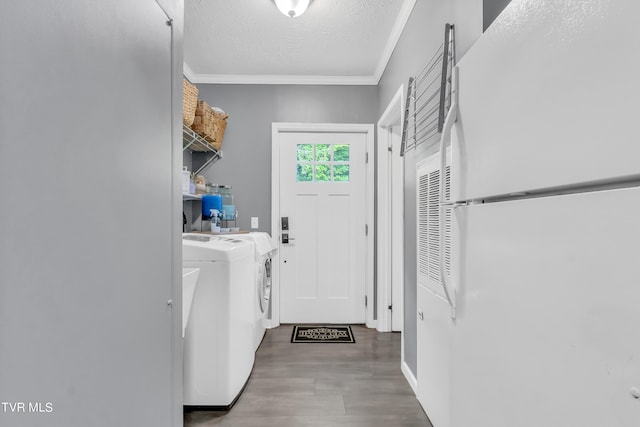 laundry room with hardwood / wood-style floors, ornamental molding, a textured ceiling, and washing machine and dryer