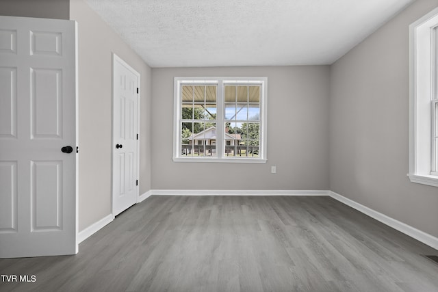 unfurnished room featuring light hardwood / wood-style floors and a textured ceiling