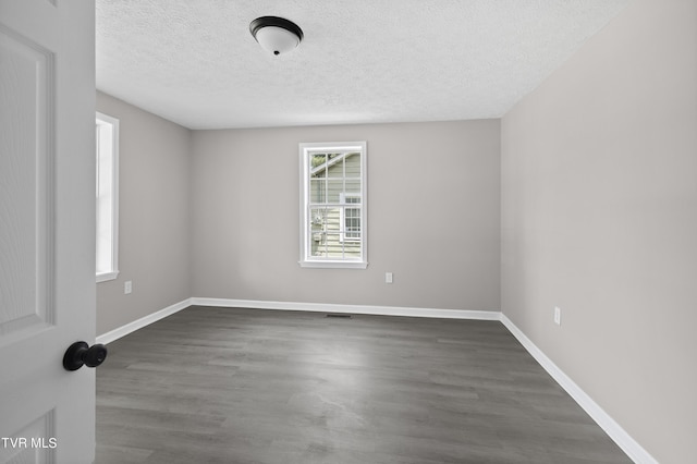 spare room featuring dark wood-type flooring and a textured ceiling