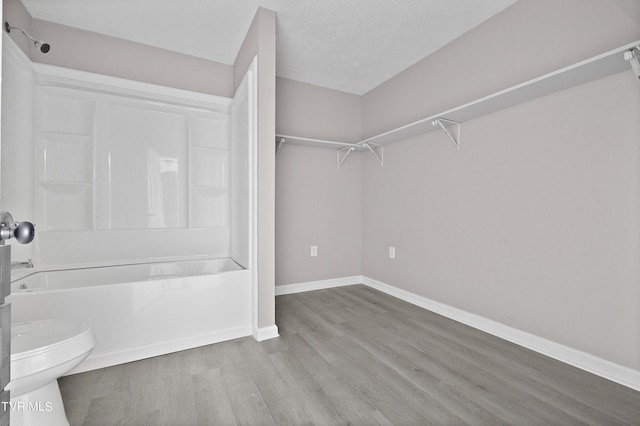 bathroom featuring hardwood / wood-style flooring, shower / tub combination, toilet, and a textured ceiling