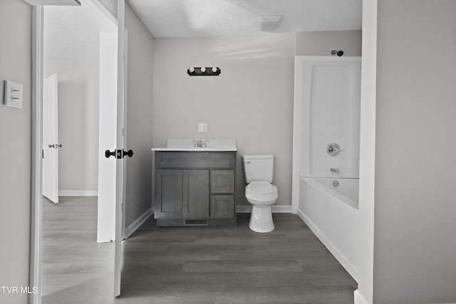 full bathroom featuring hardwood / wood-style flooring, bathing tub / shower combination, vanity, a textured ceiling, and toilet