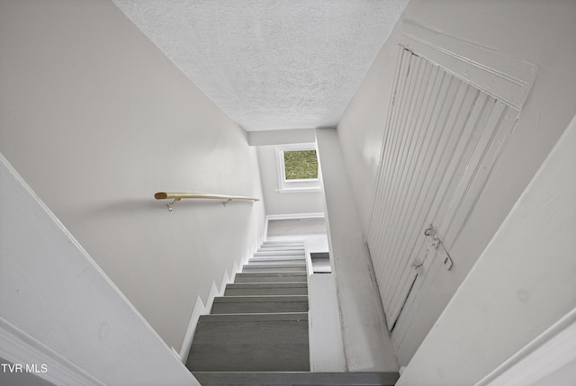 staircase featuring a textured ceiling