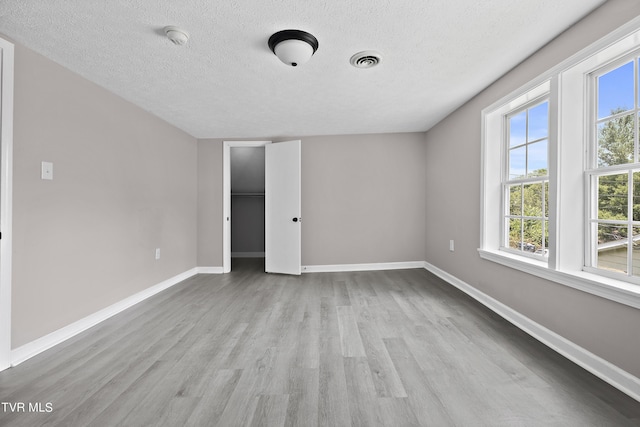 unfurnished bedroom with light hardwood / wood-style flooring and a textured ceiling