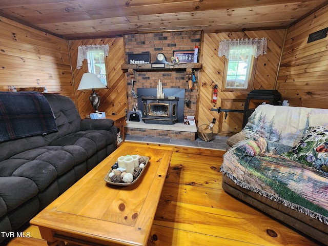 living room with wooden ceiling, wooden walls, and a wood stove