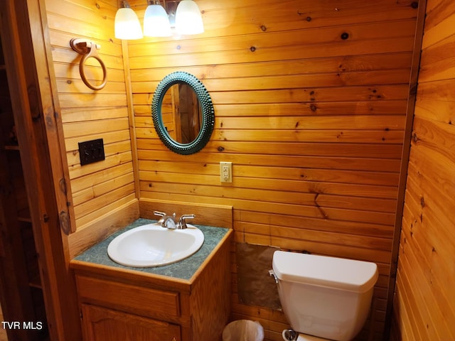 bathroom featuring wooden walls, toilet, and large vanity