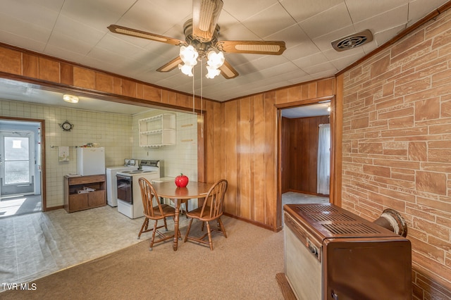 dining space with ceiling fan, wood walls, carpet flooring, and washer / dryer