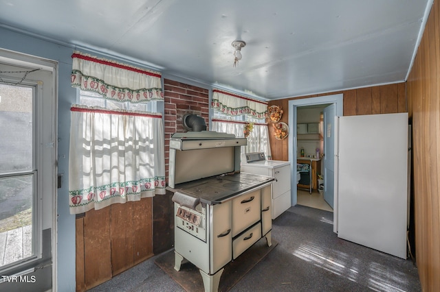 kitchen featuring stainless steel counters, wood walls, white fridge, and washer / clothes dryer