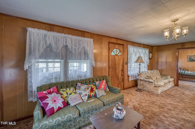 living room with an inviting chandelier, wood walls, and carpet floors