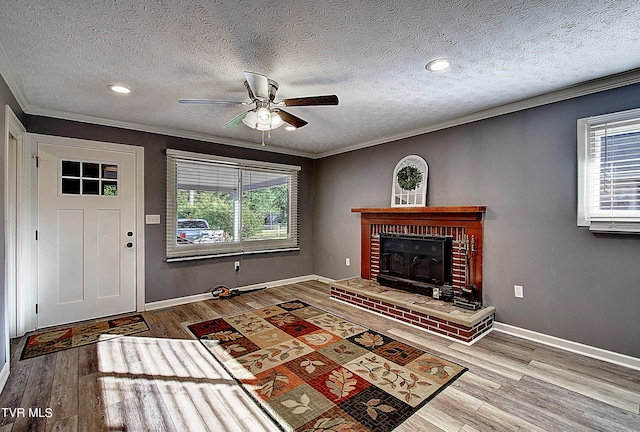 unfurnished living room with crown molding, a textured ceiling, a brick fireplace, and hardwood / wood-style floors