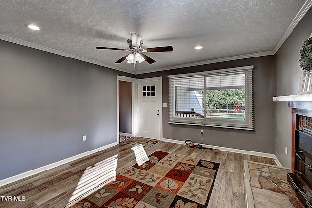 unfurnished living room with a textured ceiling, ceiling fan, hardwood / wood-style floors, and crown molding