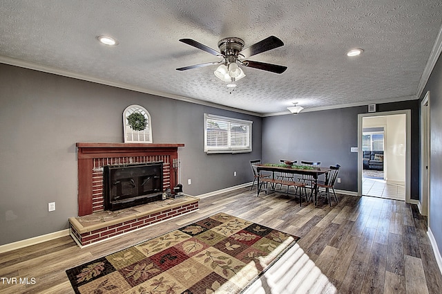 living room featuring a textured ceiling, a brick fireplace, wood-type flooring, and crown molding