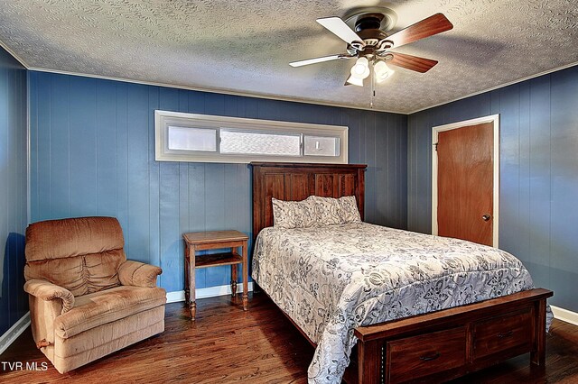 bedroom featuring a textured ceiling, dark hardwood / wood-style flooring, wooden walls, and ceiling fan