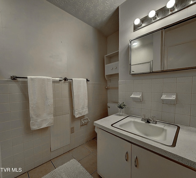 bathroom featuring tile patterned flooring, tile walls, vanity, and a textured ceiling