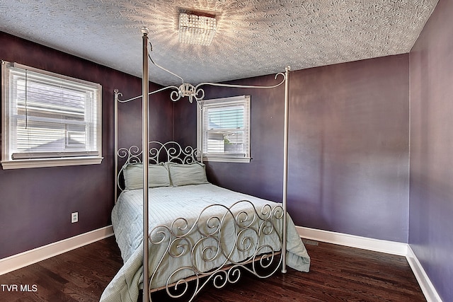 bedroom featuring multiple windows, a textured ceiling, and dark wood-type flooring