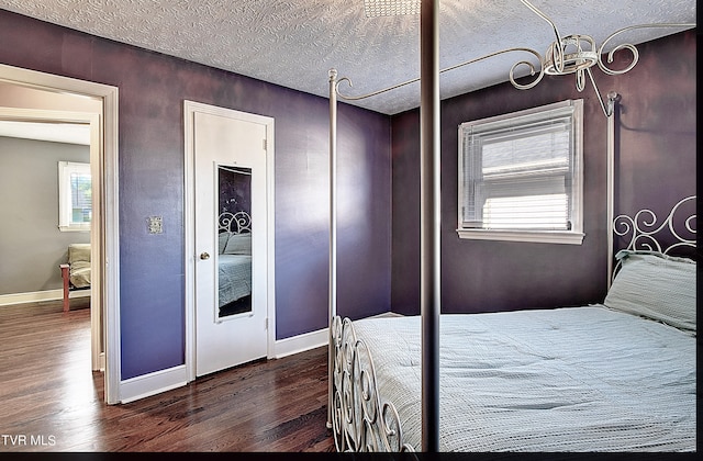 bedroom with a textured ceiling, a chandelier, and dark wood-type flooring