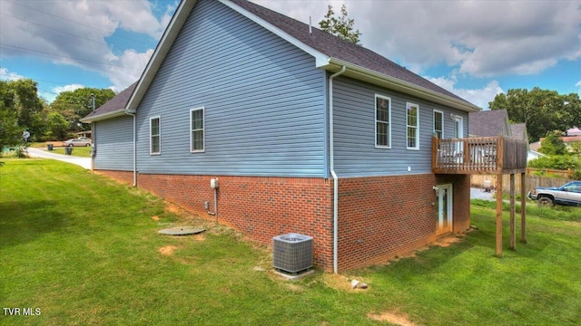 view of side of home with central AC unit and a yard