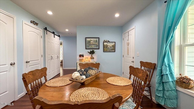 dining space with a barn door and dark hardwood / wood-style flooring