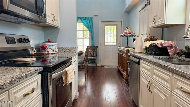 kitchen with sink, stainless steel appliances, dark hardwood / wood-style flooring, and light stone countertops