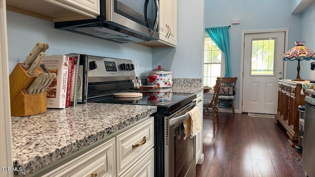 kitchen featuring appliances with stainless steel finishes, dark wood-type flooring, and light stone countertops