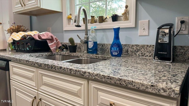 kitchen with sink, stainless steel dishwasher, and light stone countertops