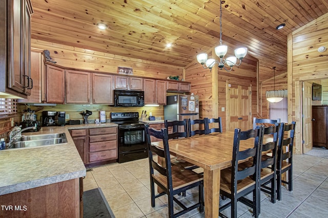 kitchen with sink, decorative light fixtures, wood walls, and black appliances