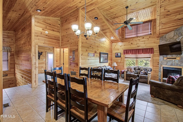 dining area with wooden walls, high vaulted ceiling, wooden ceiling, a fireplace, and light tile patterned flooring