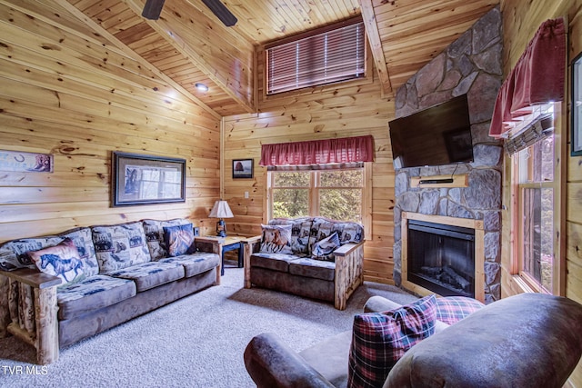 carpeted living room with a stone fireplace, wooden walls, ceiling fan, and wooden ceiling