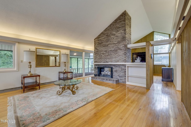 living room with a fireplace, light hardwood / wood-style floors, and vaulted ceiling